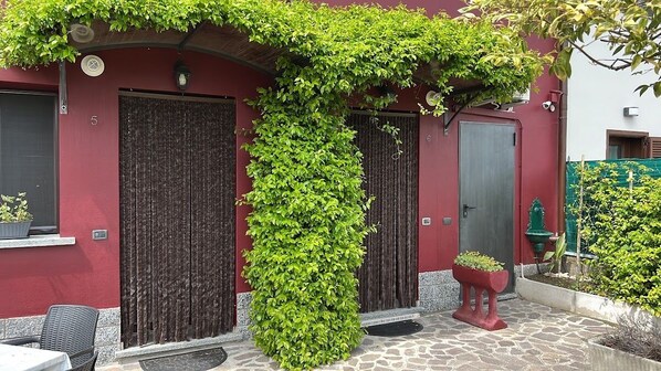 Un bâtiment à la façade rouge, doté de deux portes en bois foncé et d’une grande colonne recouverte de lierre vert.