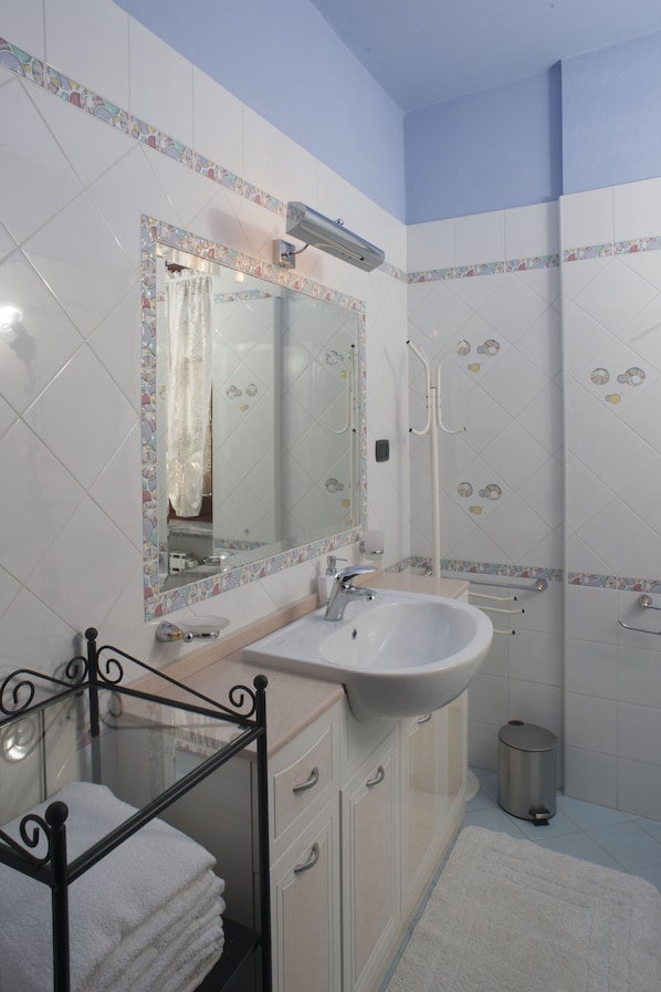 A bathroom with a white sink, a mirror, a shower, and a toilet.
