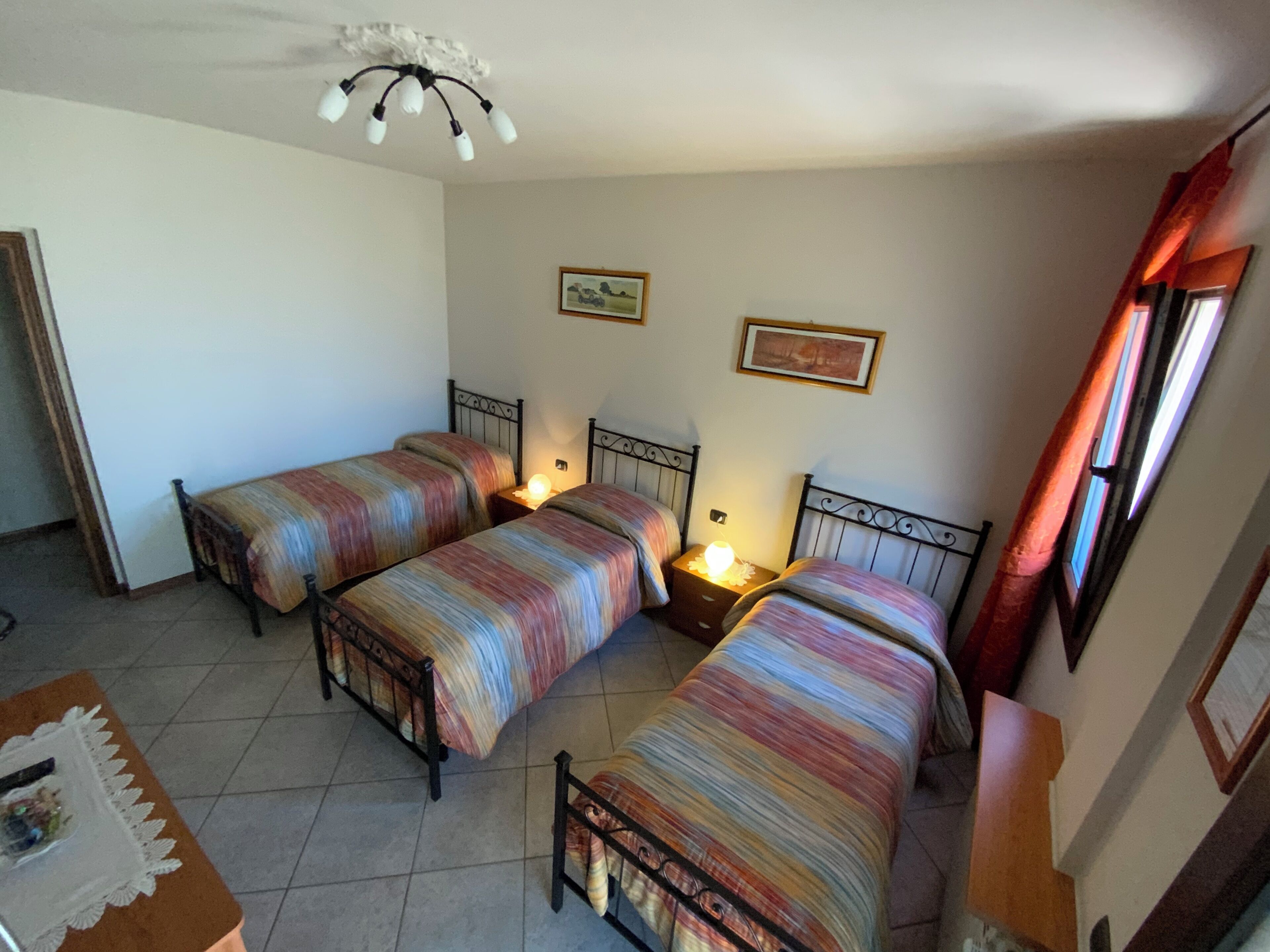 Een kamer met twee bedden, een plafondventilator en een raam met gordijnen.