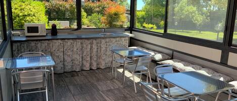 Un espacio de patio techado con mostrador de cocina, asientos y vistas al jardín.