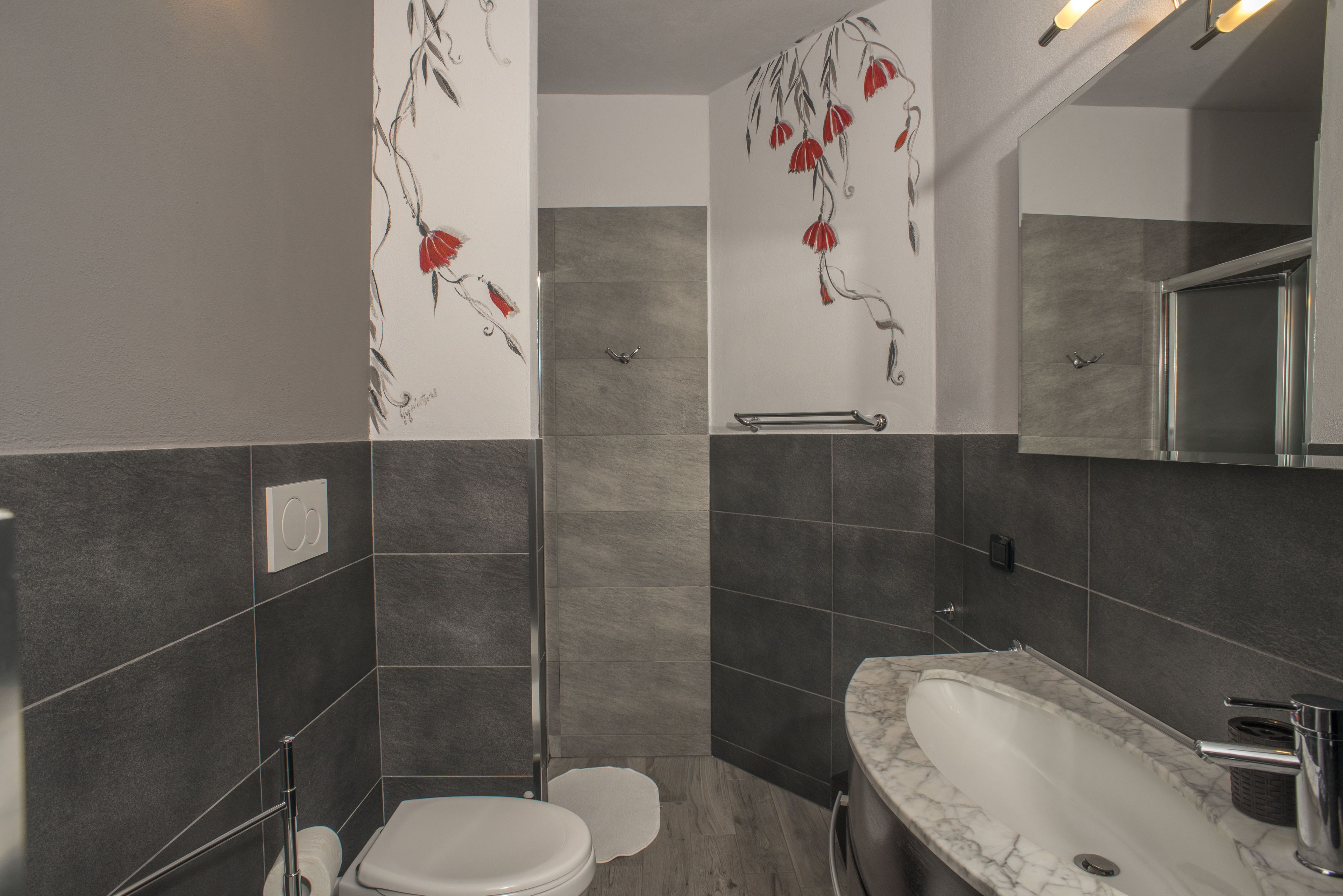 A modern bathroom with a marble sink, a toilet, and a shower area.
