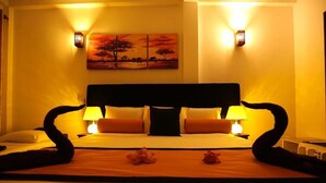 Ein Hotelzimmer mit einem großen Bett, zwei Nachttischlampen, einem Bild an der Wand und einer dekorativen Blumenanordnung auf dem Bett.