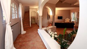 A spacious living area with a staircase, a reception desk, and a seating area. - La Pelicane (Mougins)