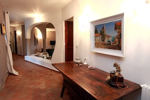 A hallway with a wooden bench, a painting, and a small table with a telephone and a container. - La Pelicane (Mougins)