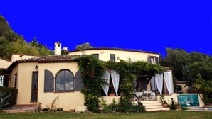A Mediterranean-style house with a tiled roof, arched windows, and a garden with a pool. - La Pelicane (Mougins)