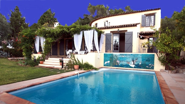 A poolside view of a Mediterranean-style house with a swimming pool, a covered patio, and a mural on the wall. - La Pelicane (Mougins)