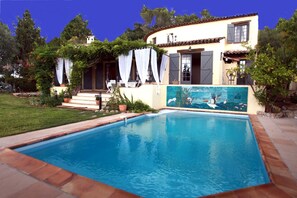 A poolside view of a Mediterranean-style house with a swimming pool, a covered patio, and a mural on the wall. - La Pelicane (Mougins)