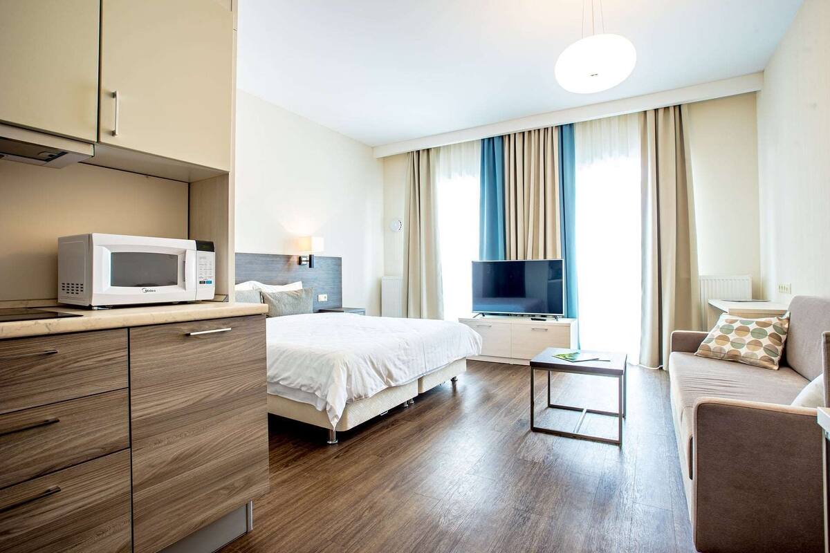 Ein Hotelzimmer mit einem Bett, einem Fernseher, einer Mikrowelle, einer Couch und einem kleinen Tisch.