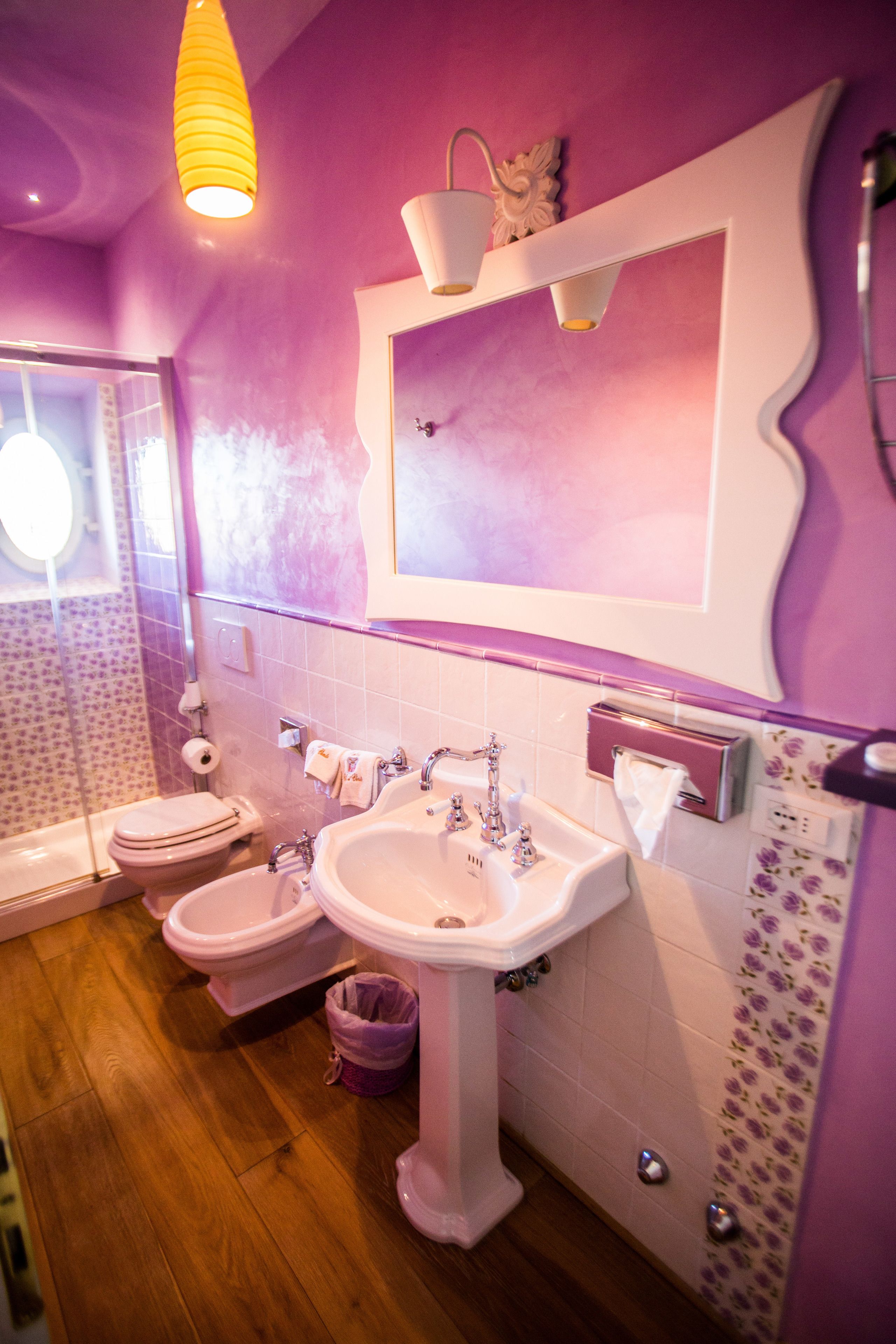 Un baño con suelo de madera, dos inodoros, un lavabo y un espejo.