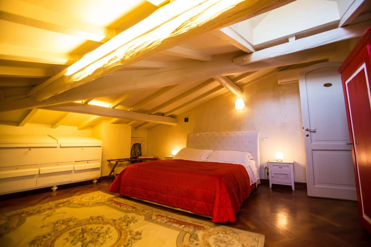 Une chambre à coucher avec une couvre-lit rouge, un plafond en bois et une armoire blanche.