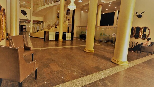 A spacious lobby with a grand staircase, a reception desk, and a seating area. - Treasures Suites & Conferences (Abuja)