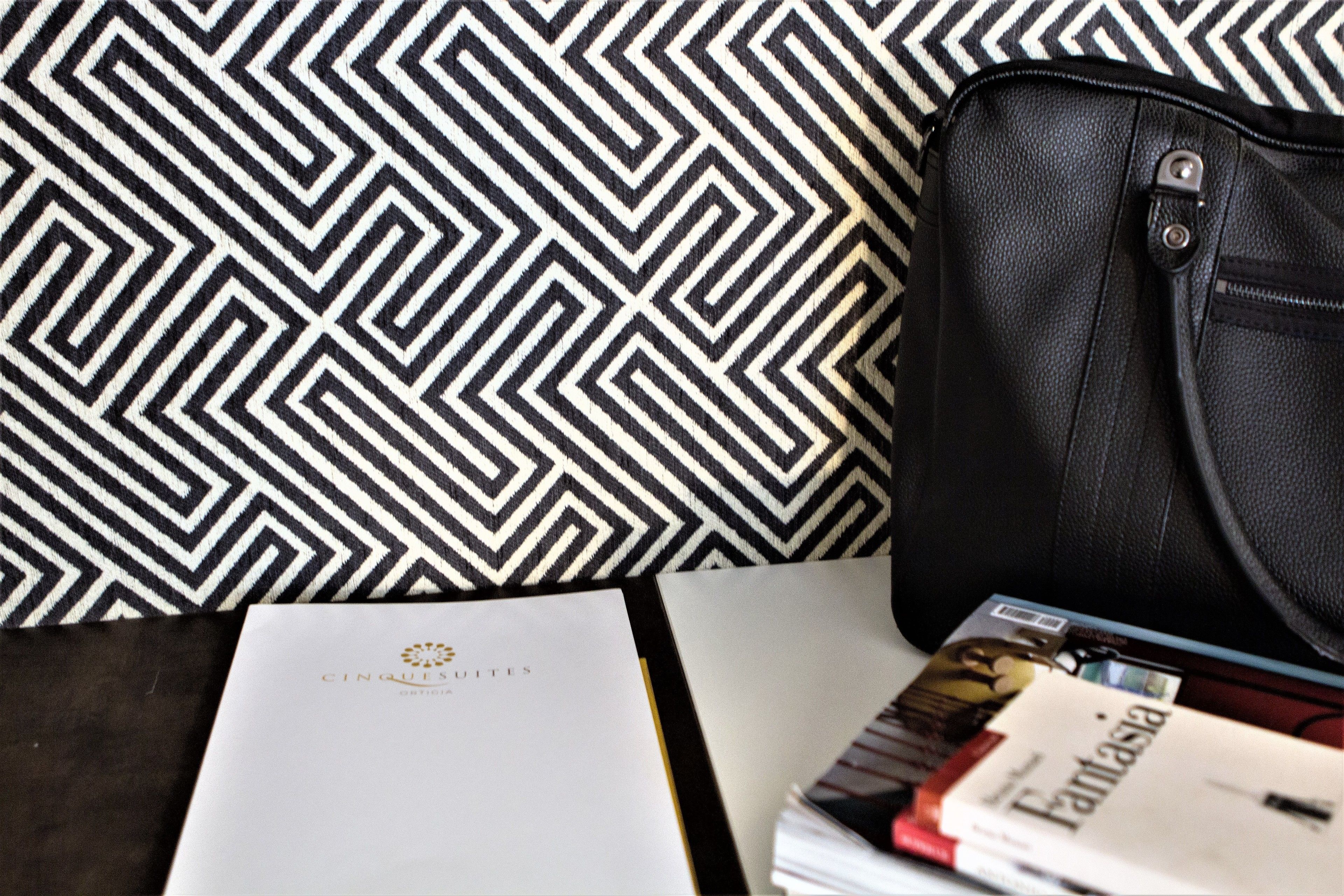 A black leather bag, a white booklet with 'Cinqués' logo, and a magazine titled 'Fantasia'.