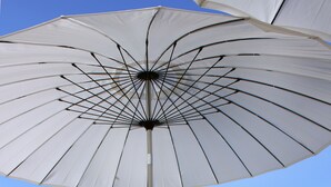 An outdoor seating area with a table, a blue vase, and a white umbrella. - CinqueSuites Ortigia (Syracuse)
