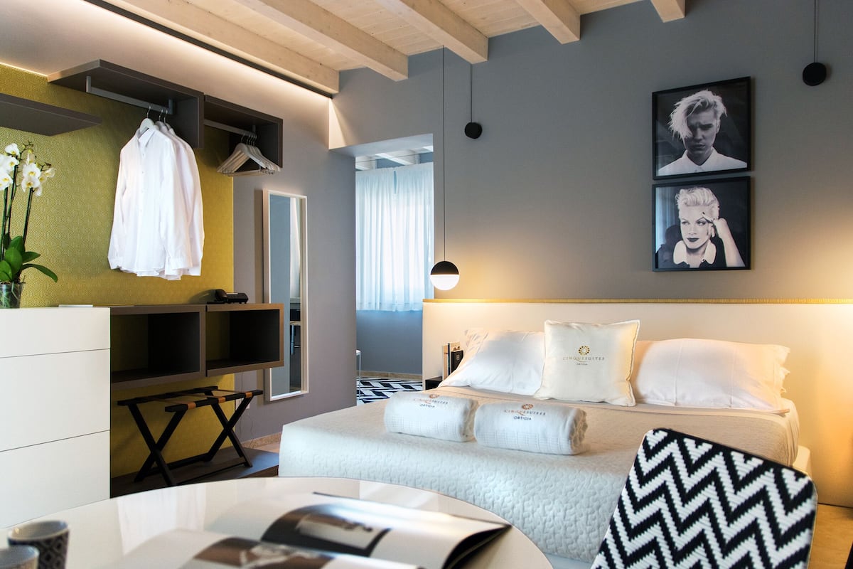 A modern hotel room with a bed, a desk, a chair, and a TV.