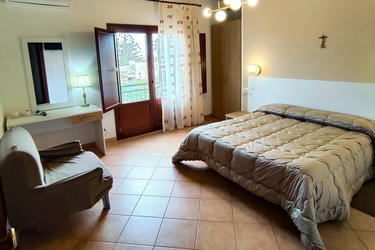Ein Schlafzimmer mit Bett, Schreibtisch, Stuhl und einem Fenster mit Vorhängen.