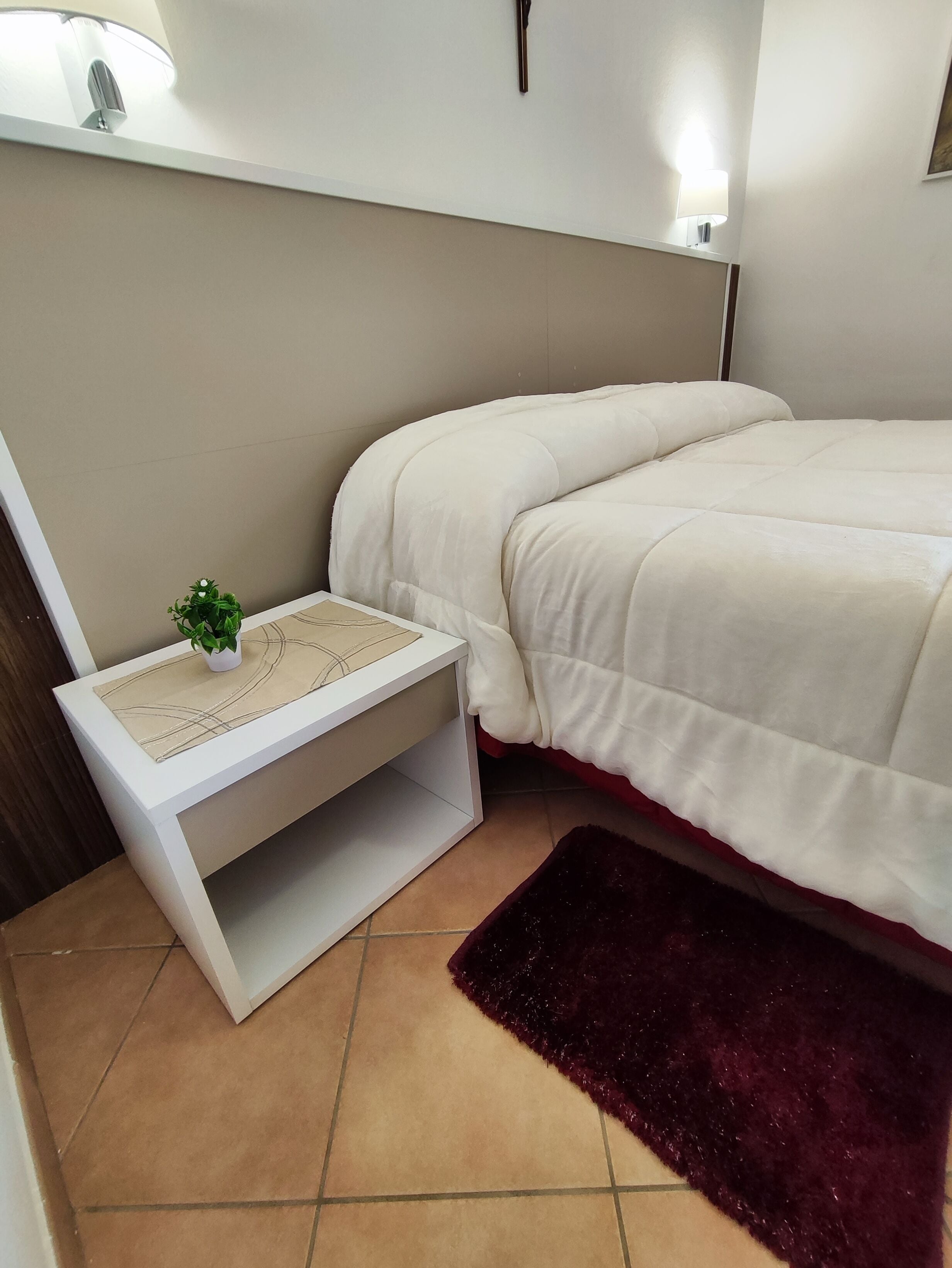 Une chambre à coucher avec un lit, une table de chevet et une petite plante en pot.