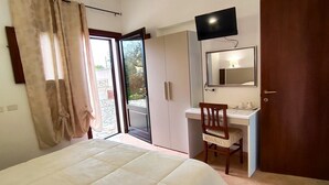 Ein Schlafzimmer mit einem Bett, einem Schreibtisch, einem Stuhl, einem Fernseher und einer Schiebetür.