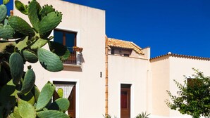 Ein Gebäude mit Balkon und Tür, umgeben von Kakteen.