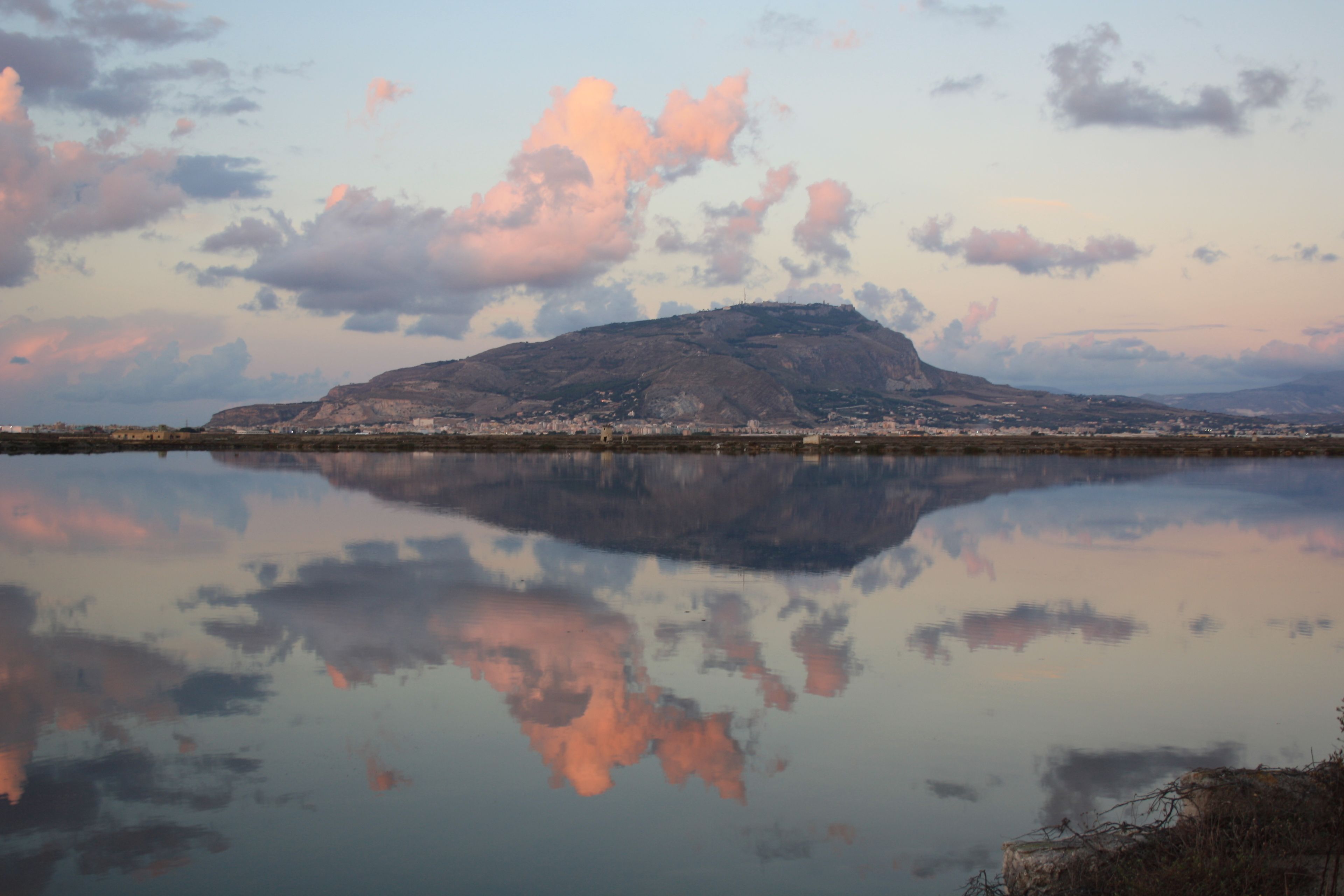 Una montaña reflejada en aguas tranquilas, con un pueblo al fondo.