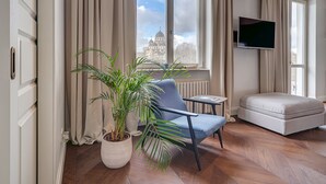 Una sala de estar moderna con un ventanal grande, una planta en maceta, un sillón azul, una mesita y un sofá.