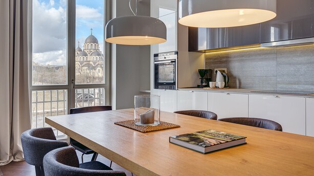 Una cocina moderna con un ventanal grande, una mesa de comedor con sillas y vistas a un edificio histórico.