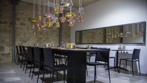Un espace de salle à manger moderne avec une longue table, des chaises noires et des luminaires suspendus.