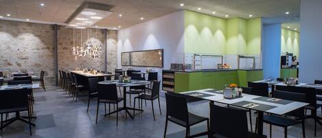 A modern dining area with tables and chairs, a stone wall, and a green accent wall.