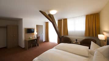 A hotel room with a bed, desk, chair, television, and a window with curtains.