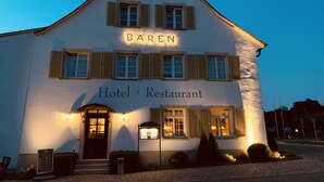 Un bâtiment blanc portant l’inscription « Gasthof Bären » et les panneaux « Hôtel-restaurant ». Il présente un style architectural européen traditionnel, avec un toit à pignon et des volets aux fenêtres.