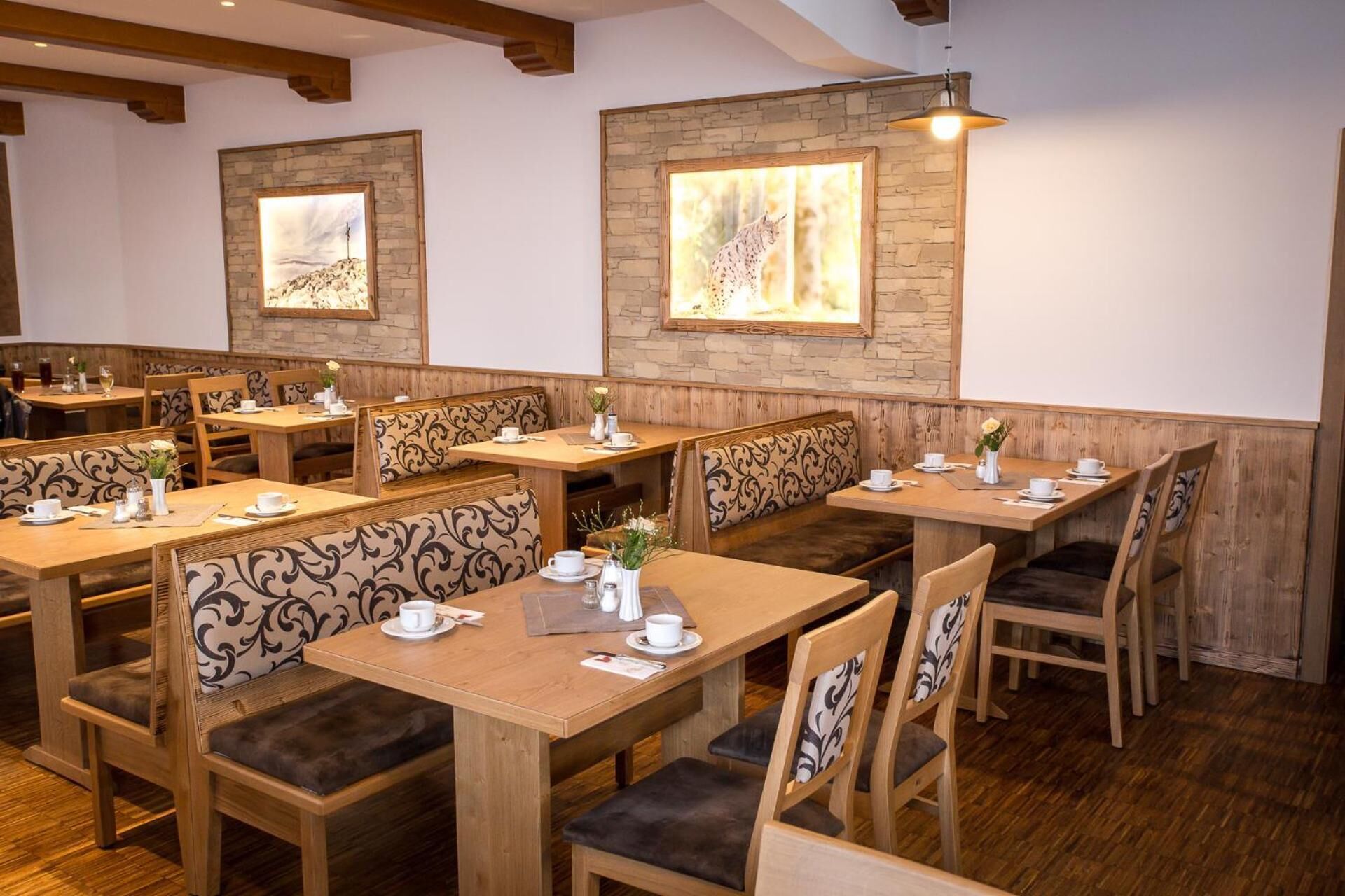 A restaurant with wooden tables and benches, stone walls, and framed artwork.