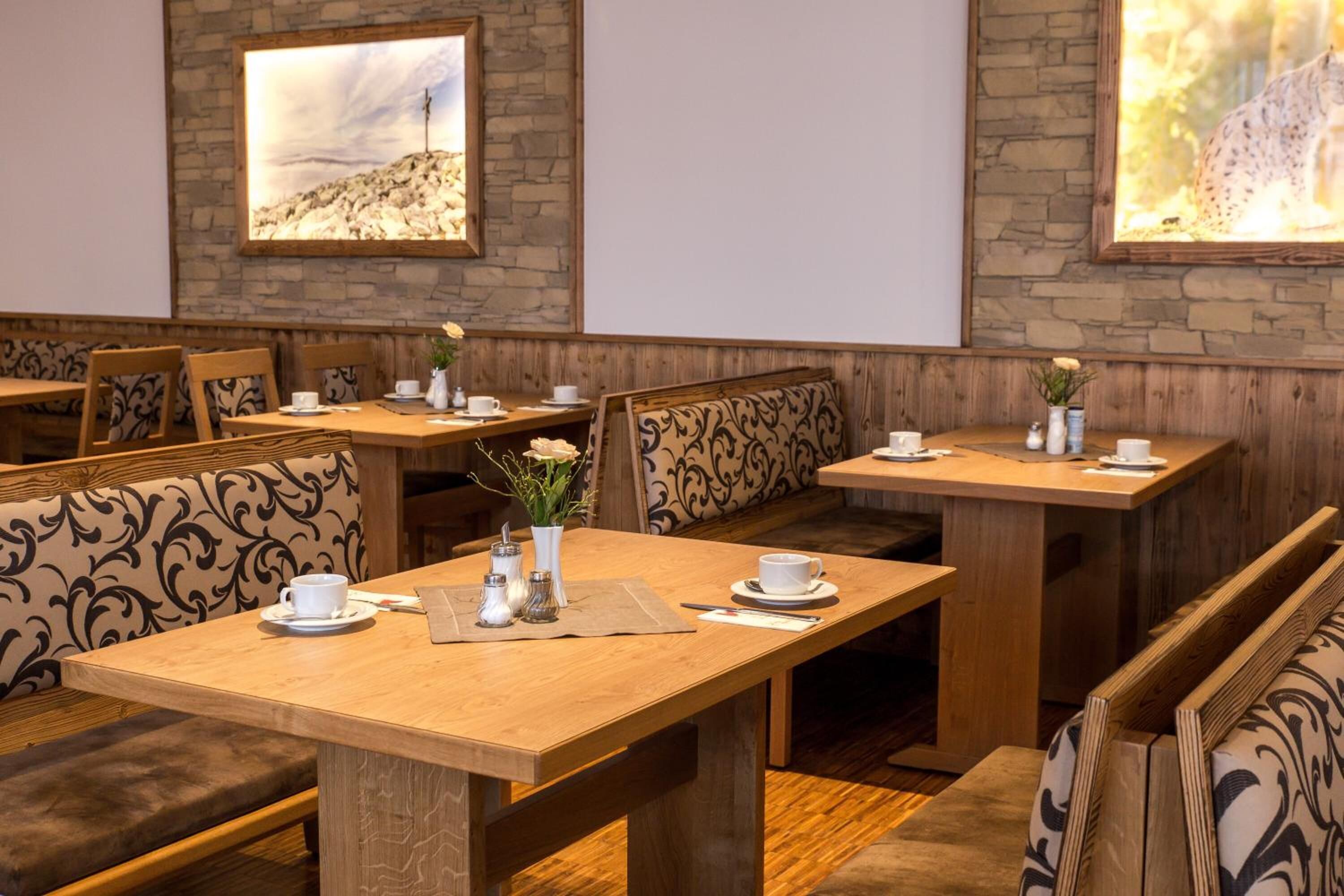 Ein Restaurant mit Holztischen, gepolsterten Sitzbänken, gerahmten Bildern an den Wänden und einem sauberen, modernen Ambiente.
