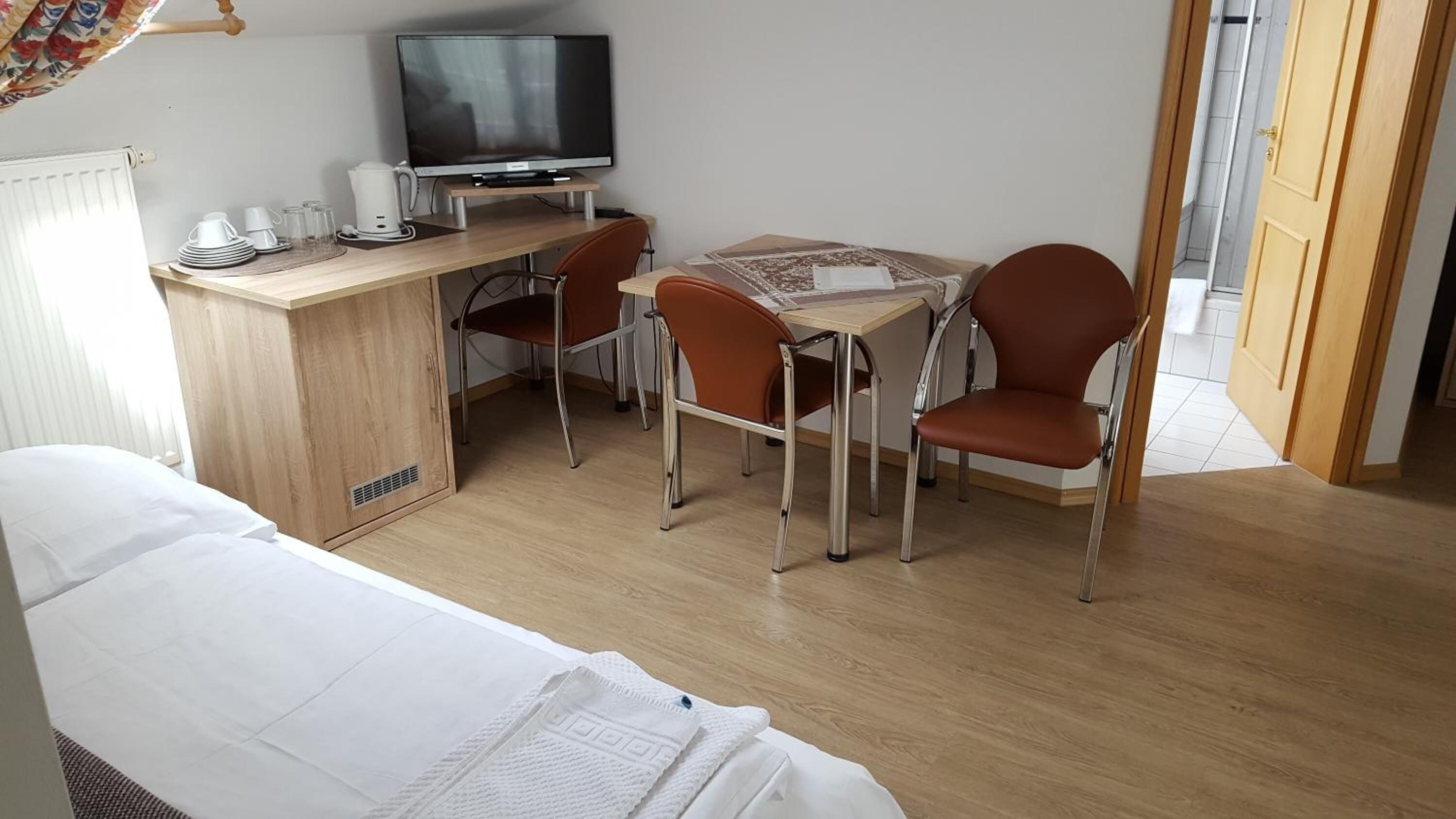 Une chambre d’hôtel comprenant un lit, un bureau avec une télévision, deux chaises et une petite table.
