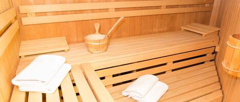 Una sauna de madera con bancos y un cubo de madera con una cuchara.