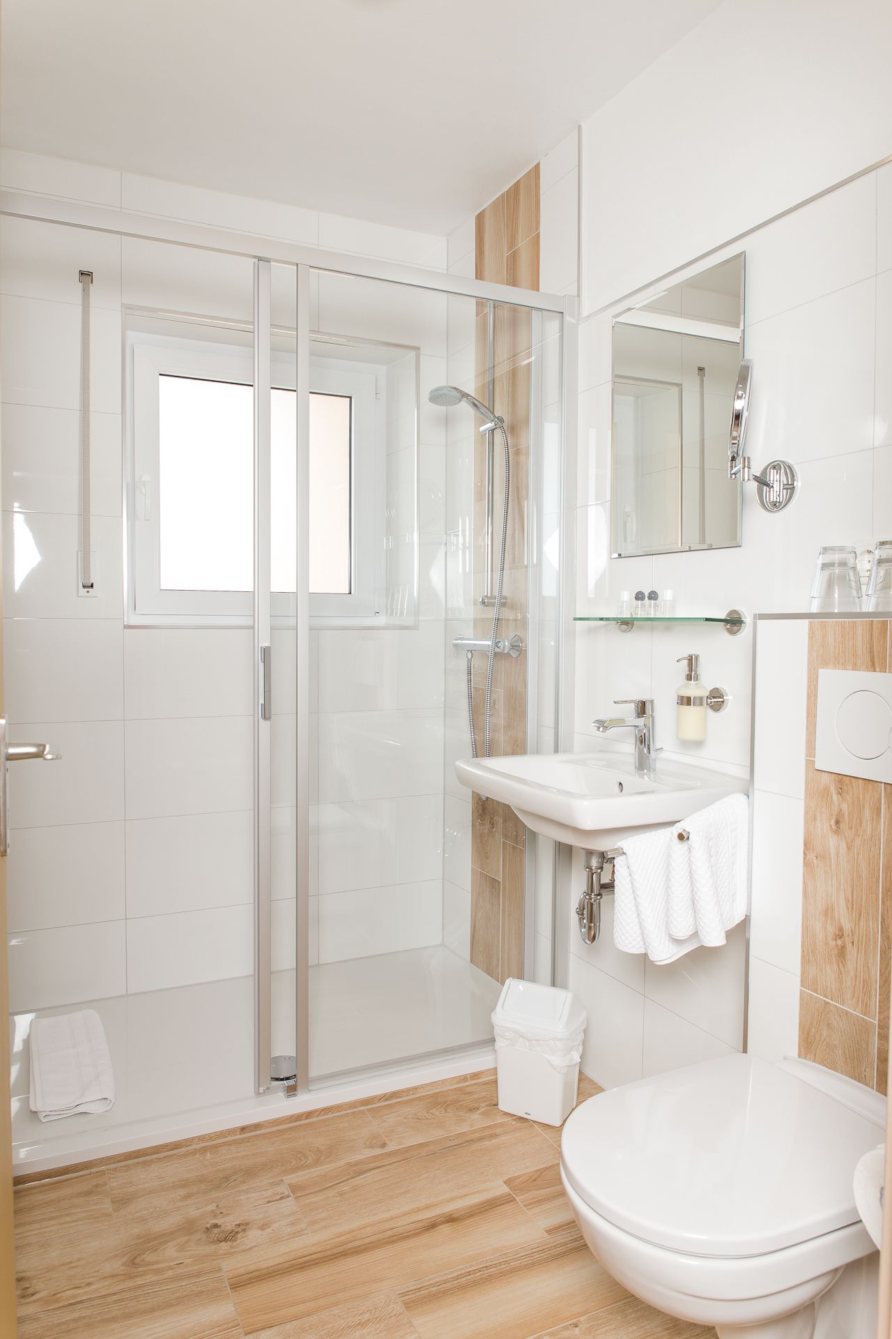 Une salle de bain moderne avec une douche à parois de verre, un lavabo blanc et des toilettes.