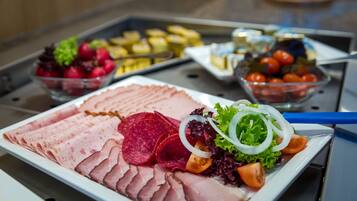 A buffet with various food items including sliced meats, salads, and fruits.