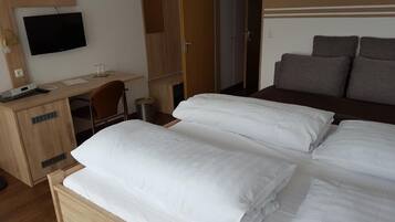 A hotel room with a bed, a desk, a chair, a TV, and a wardrobe.