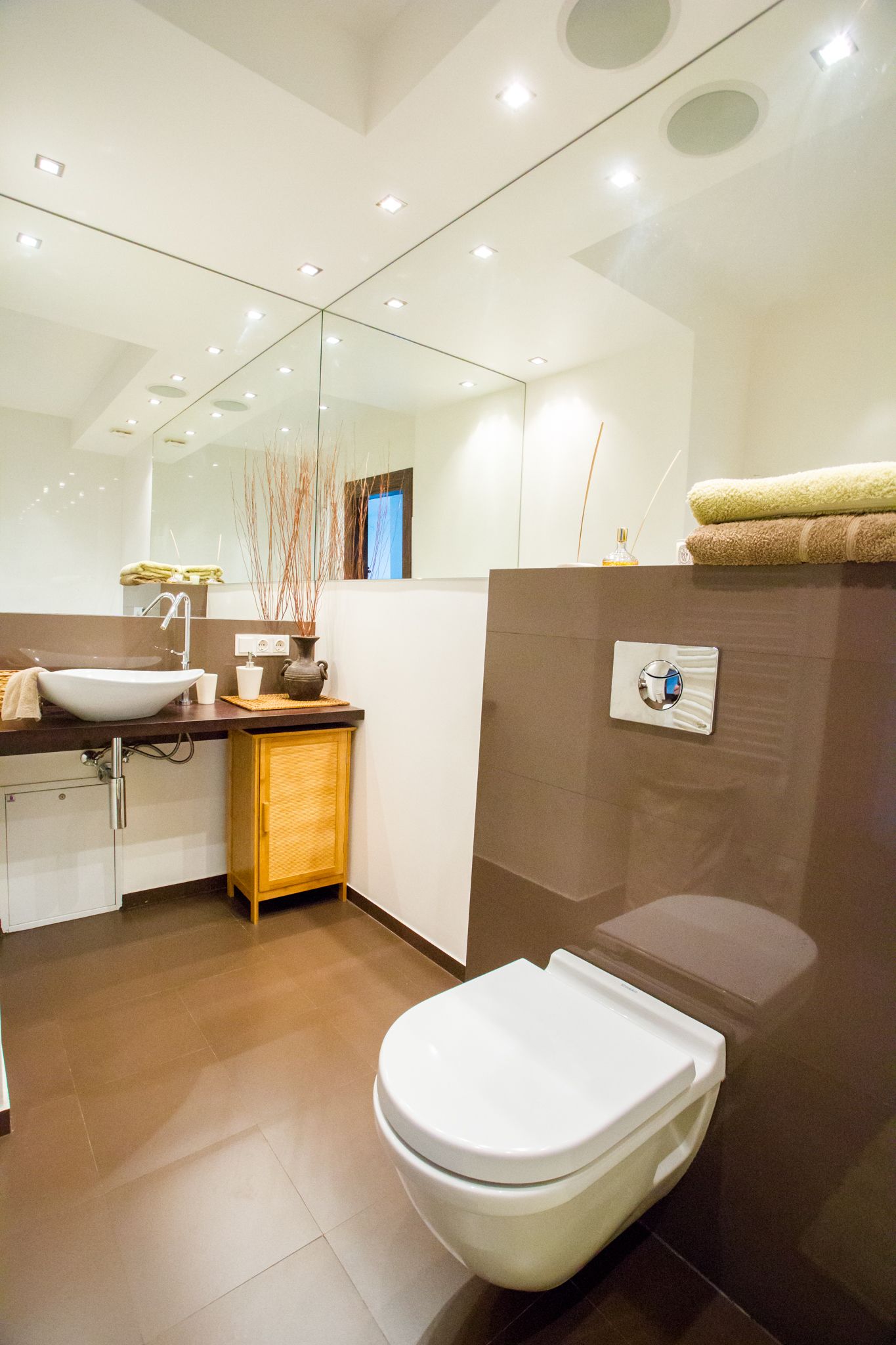 A modern bathroom with a white sink, mirror, and toilet.