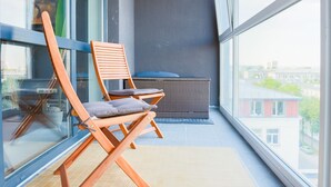Un balcon avec deux chaises en bois et une vue sur la ville.