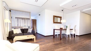 Un salon moderne avec un canapé, une table à manger et des chaises, et un plancher en bois.