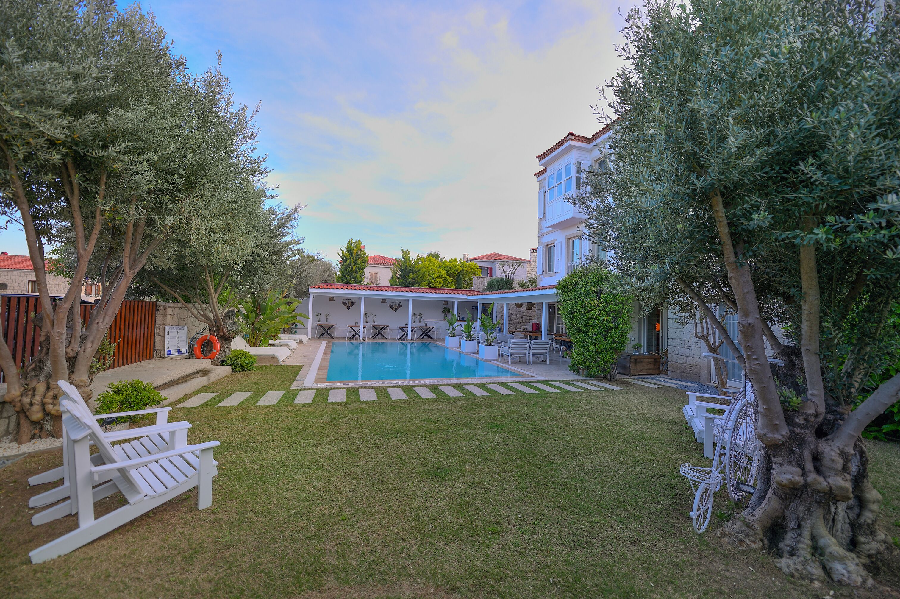 A pool area with a lawn, a white chair, and a bicycle.