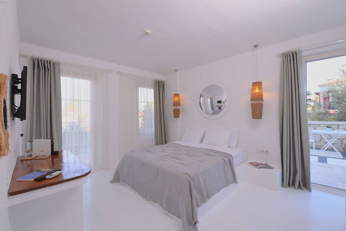 A bedroom with a bed, bedside table, lamp, and curtains.