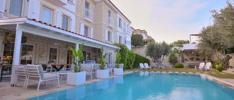 Una piscina al aire libre, sombrillas, sillones reclinables de piscina