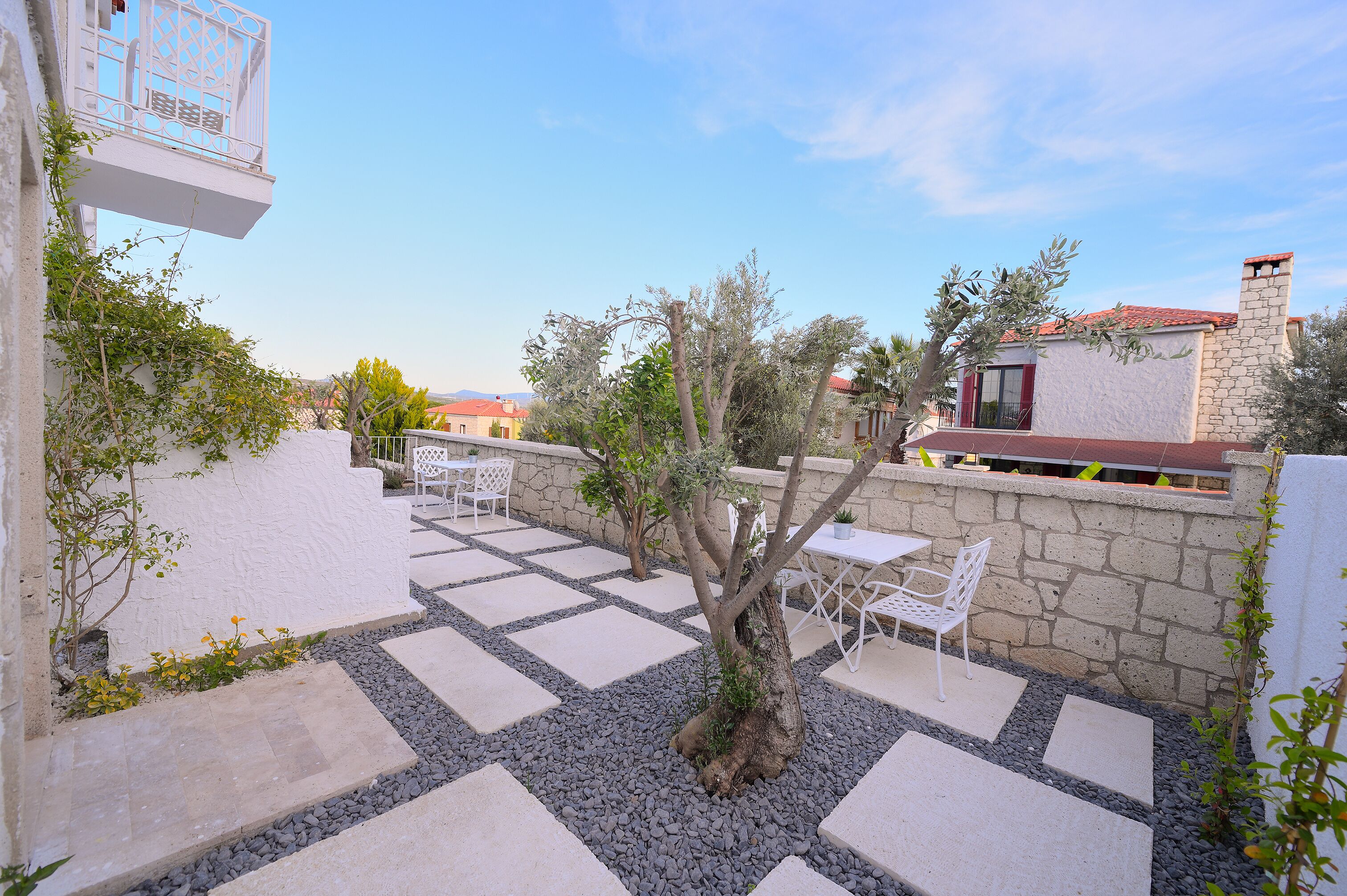 A courtyard with stone walls, a tree, and outdoor seating.
