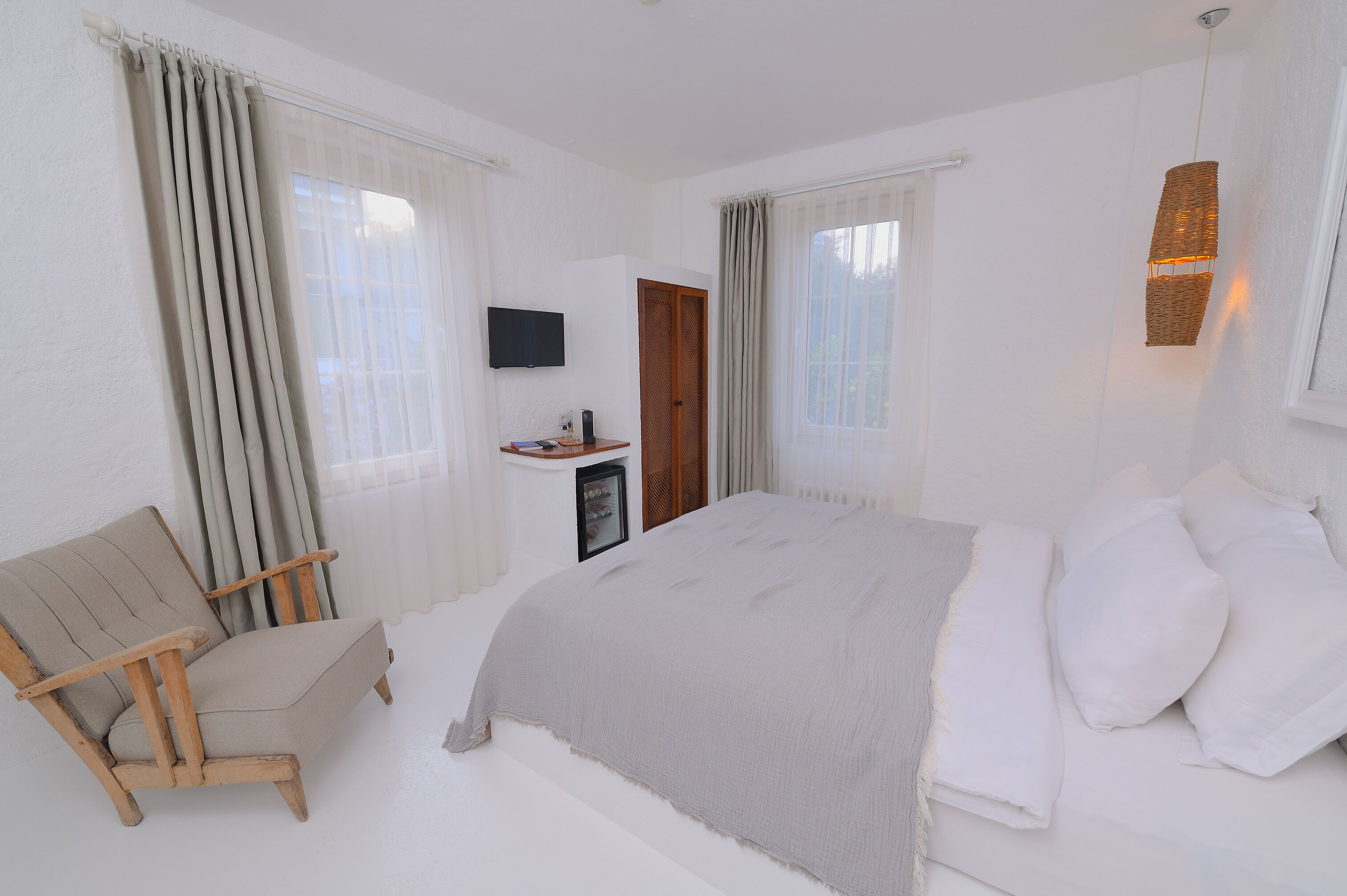 Un dormitorio con una cama, una silla de madera, un televisor y una mesita.