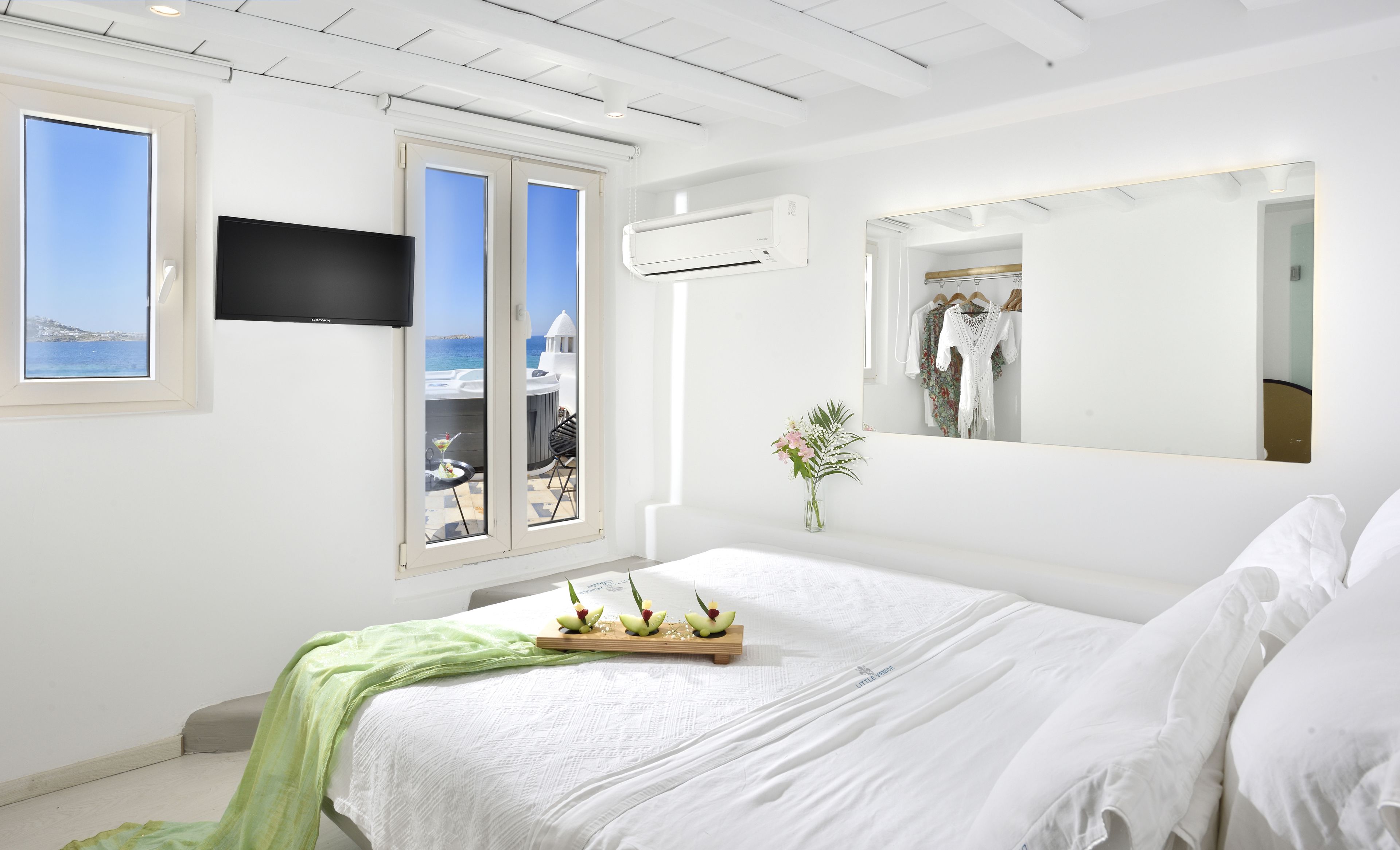 Une chambre à coucher avec un lit, une télévision, une fenêtre donnant sur un beau paysage et un miroir.