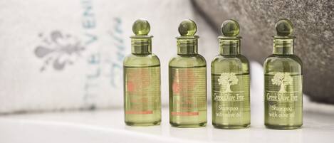Four bottles of Greek Olive Tree shampoo with olive oil on a white surface.