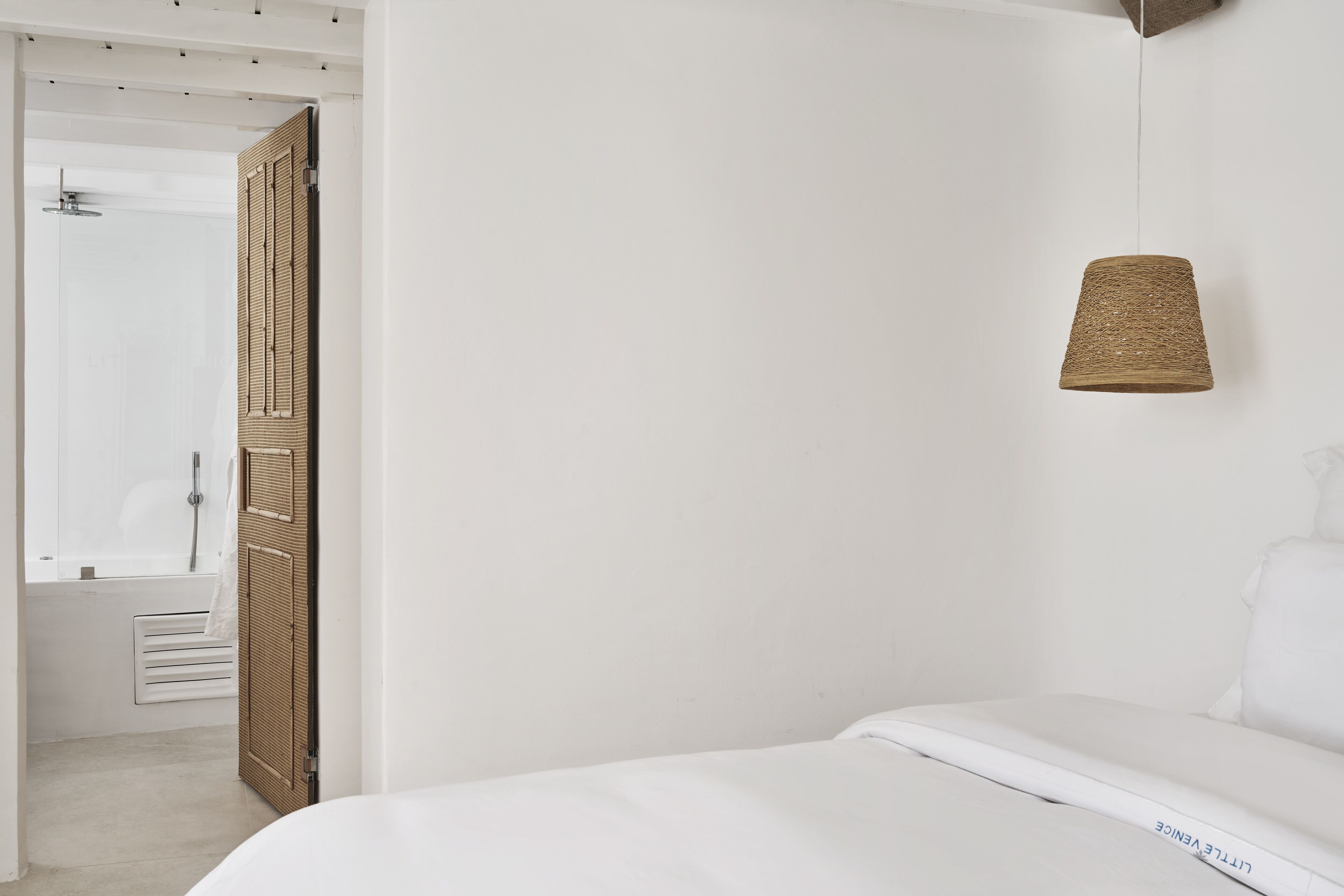 Un dormitorio con cama, lámpara colgante y puerta que da a un baño.