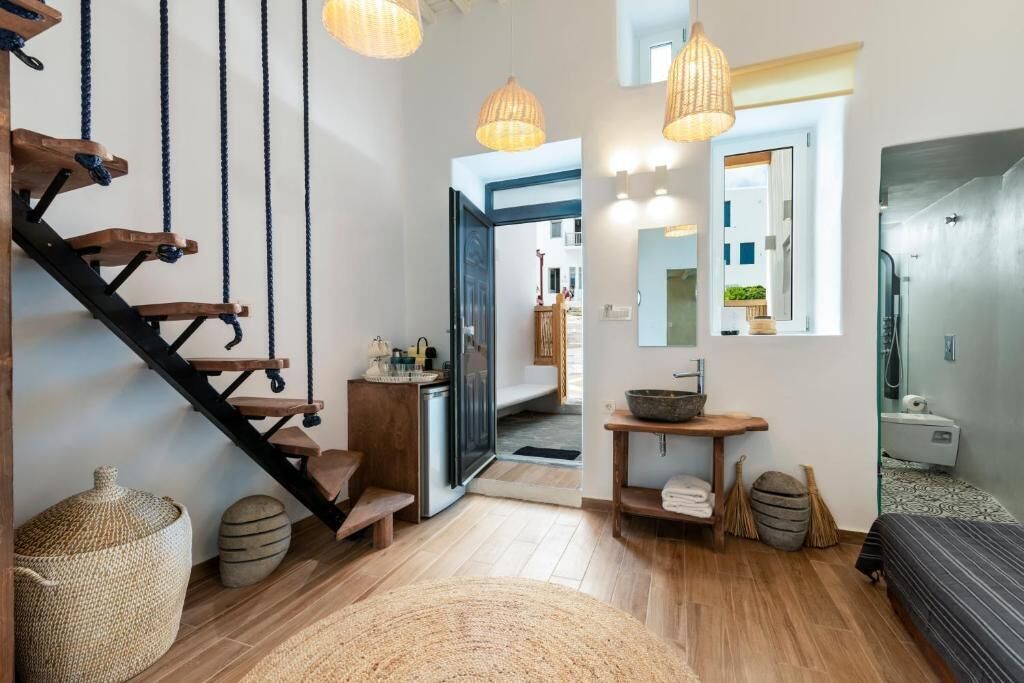 Ein modernes Interieur mit einer Holztreppe, einer kleinen Küchenzeile, einem Badezimmer und einem großen Spiegel.