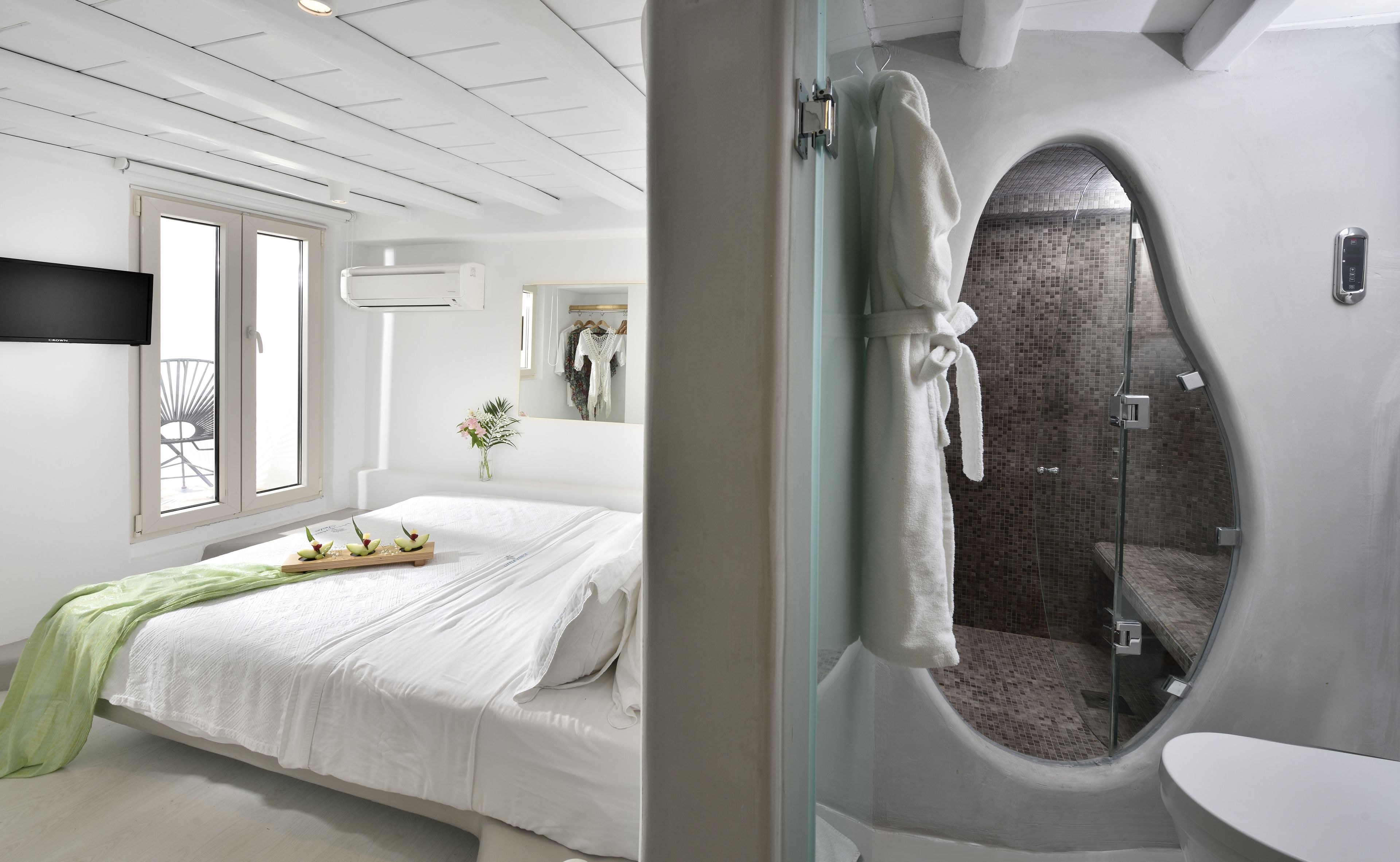 Ein modernes Schlafzimmer mit Bett, Schminktisch und Duschbereich.