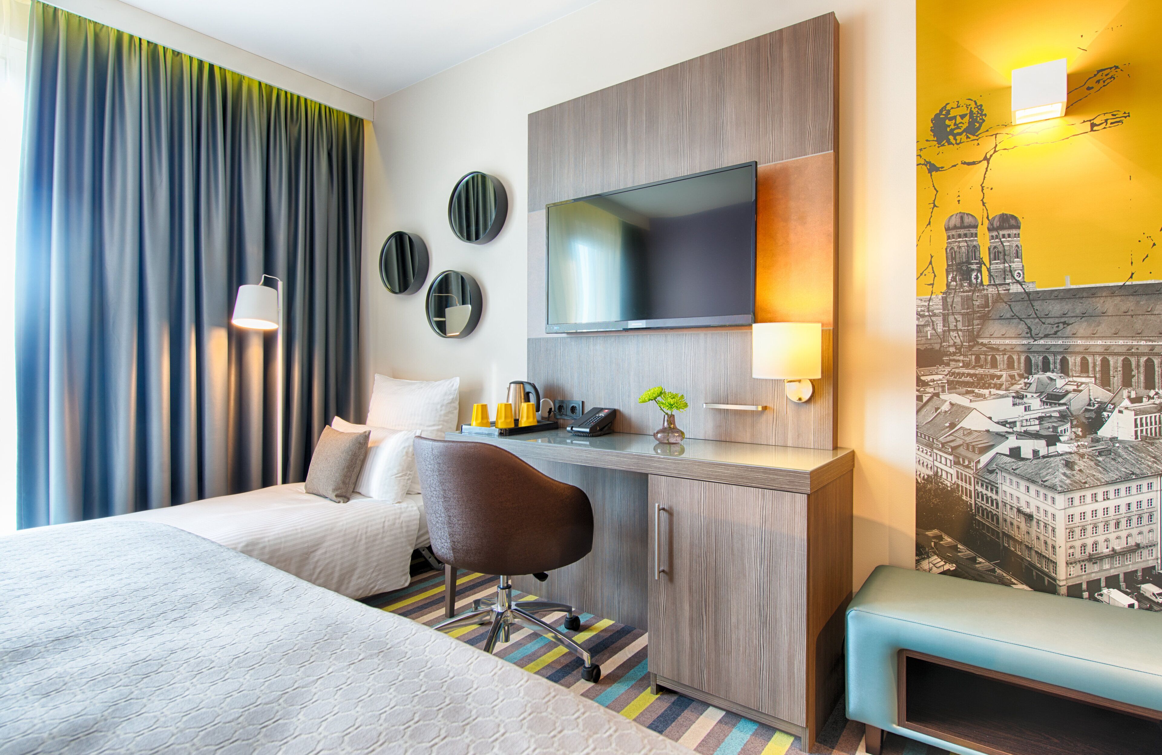 A hotel room with a bed, desk, chair, and a television.